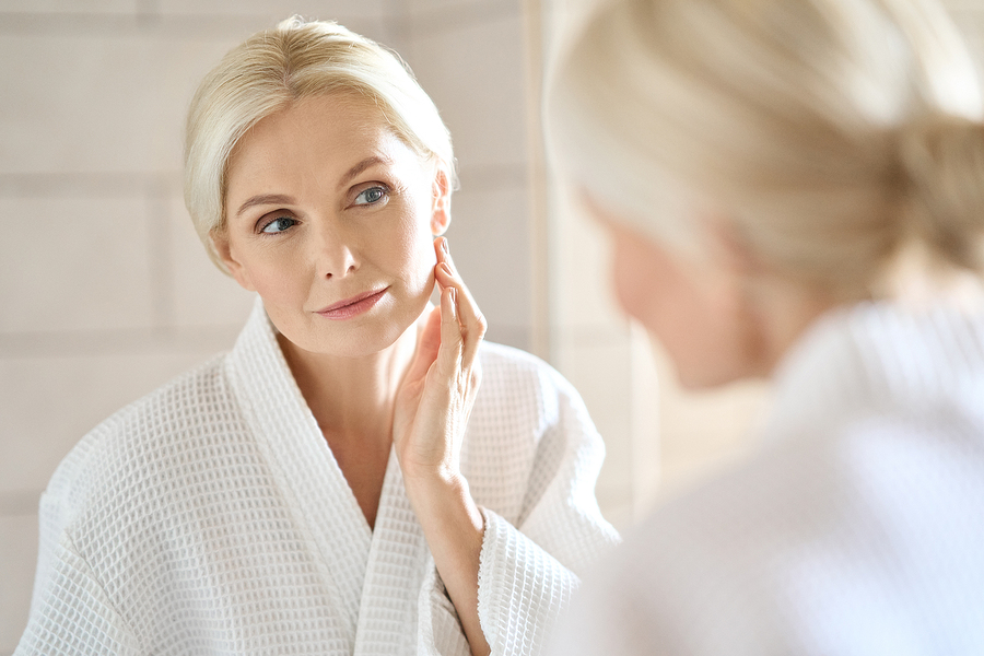 pretty blonde mid age woman looking at face in mirror