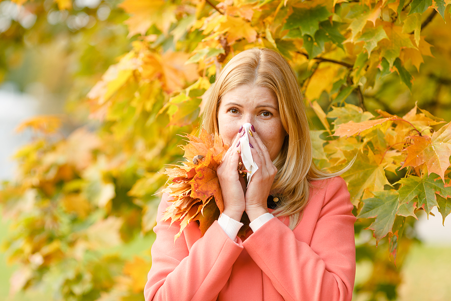 blonde woman kleenex in front of fall tree