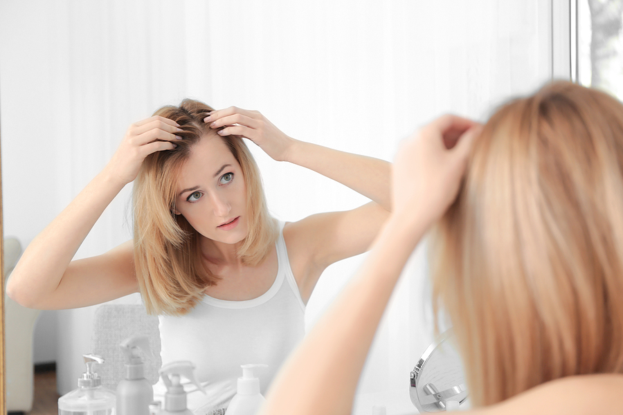 blonde woman looking at hair in mirror
