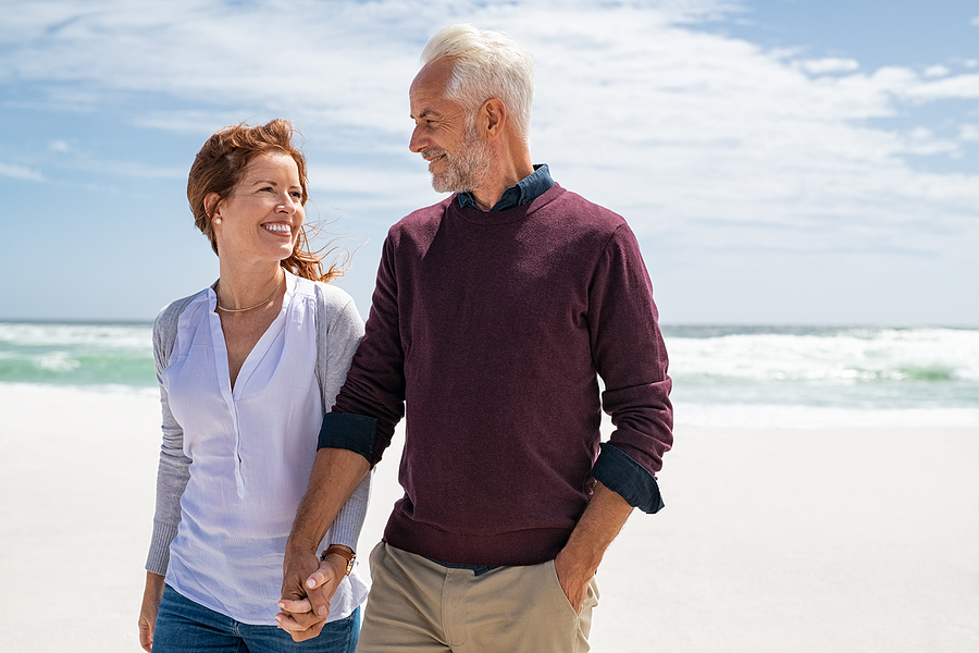 couple holding hands walking on beach