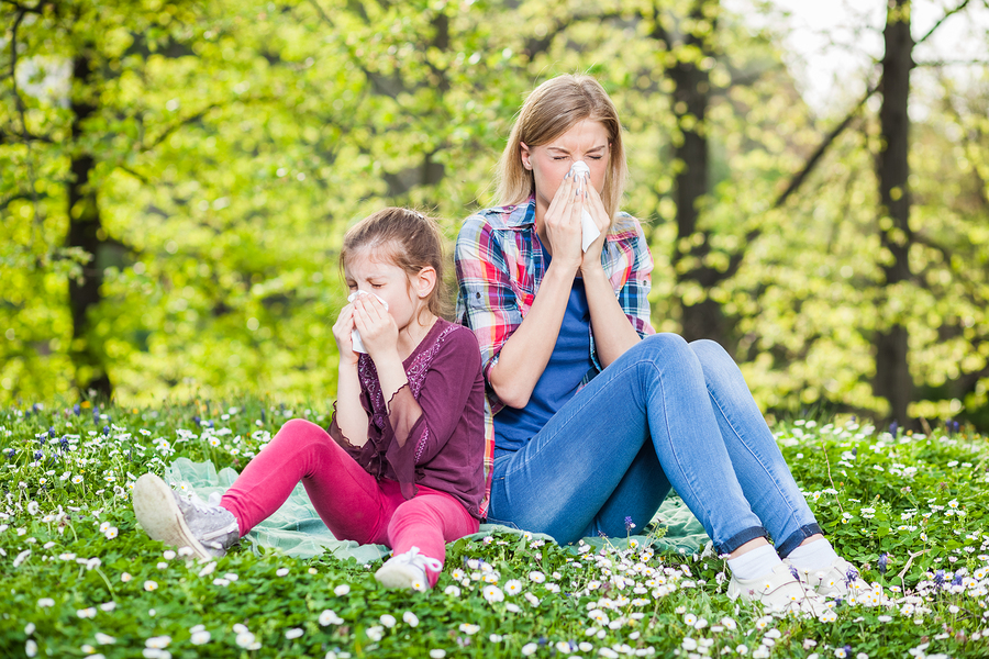 mom and daughter outside on grass sneezing