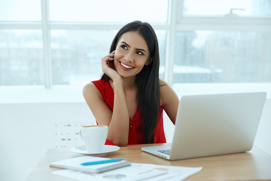 dark hair woman in red top thinking at desk