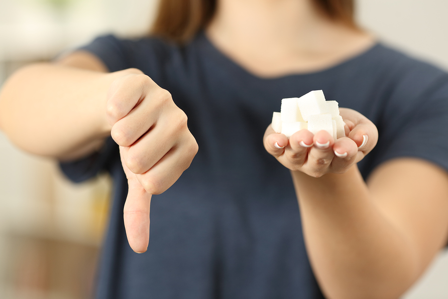 woman holding sugar in one hand and thumbs down with other hand