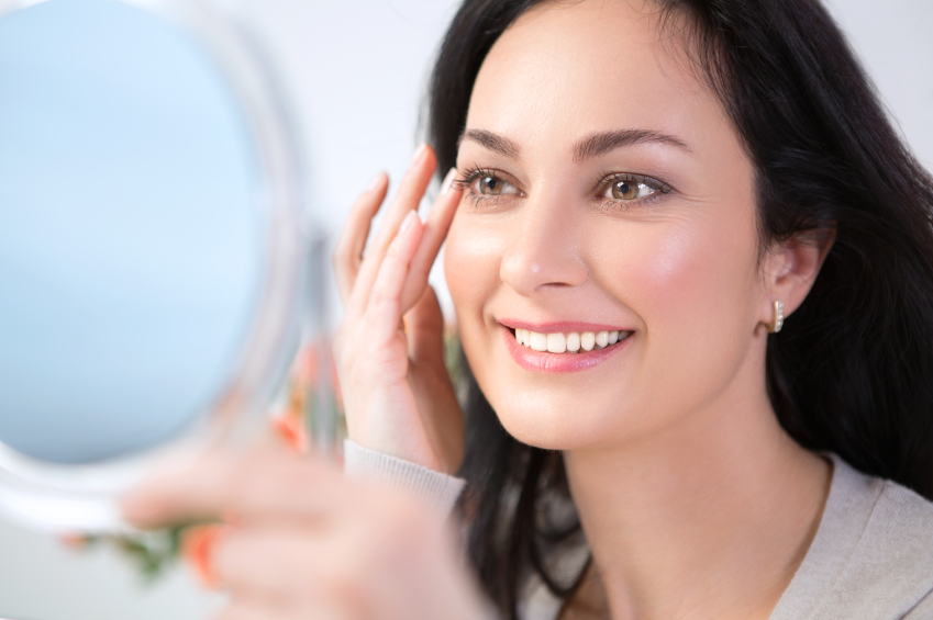 woman smiling looking in mirror beautiful skin