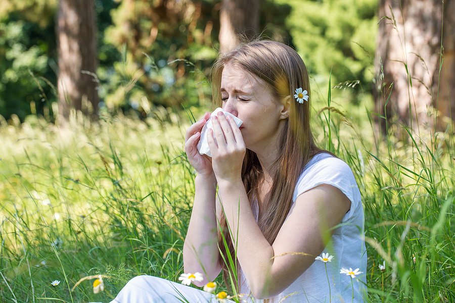 young girl sitting in grass sneezing