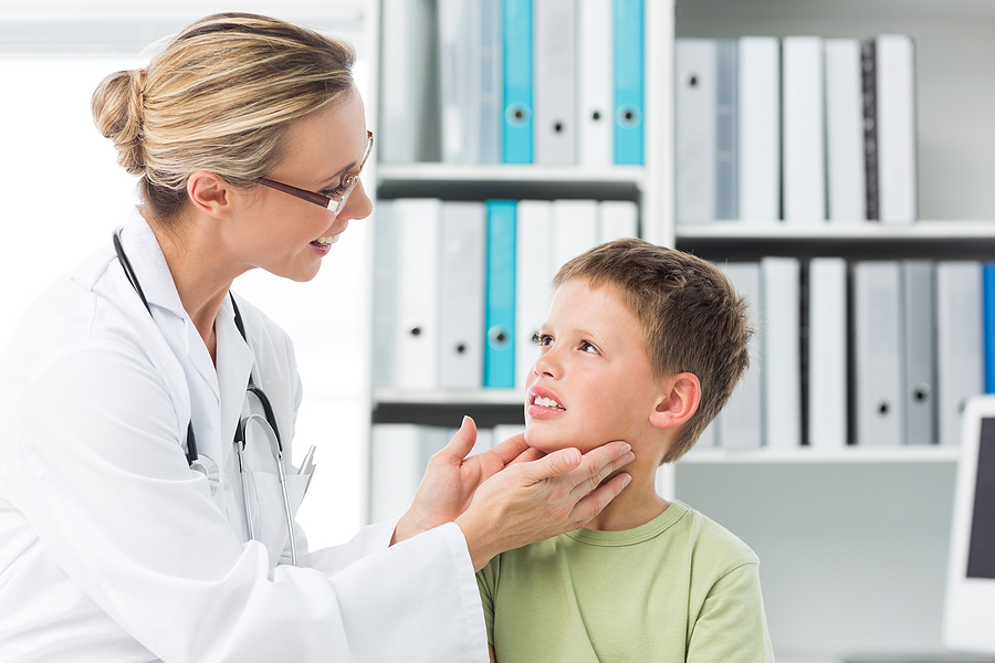 female doctor examining thyroid of young boy