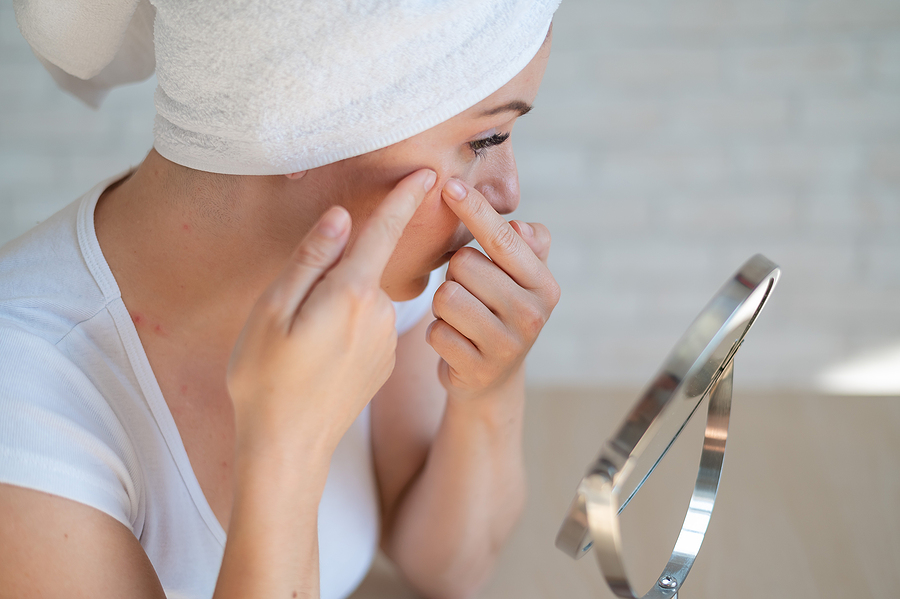 woman looking at acne in mirror