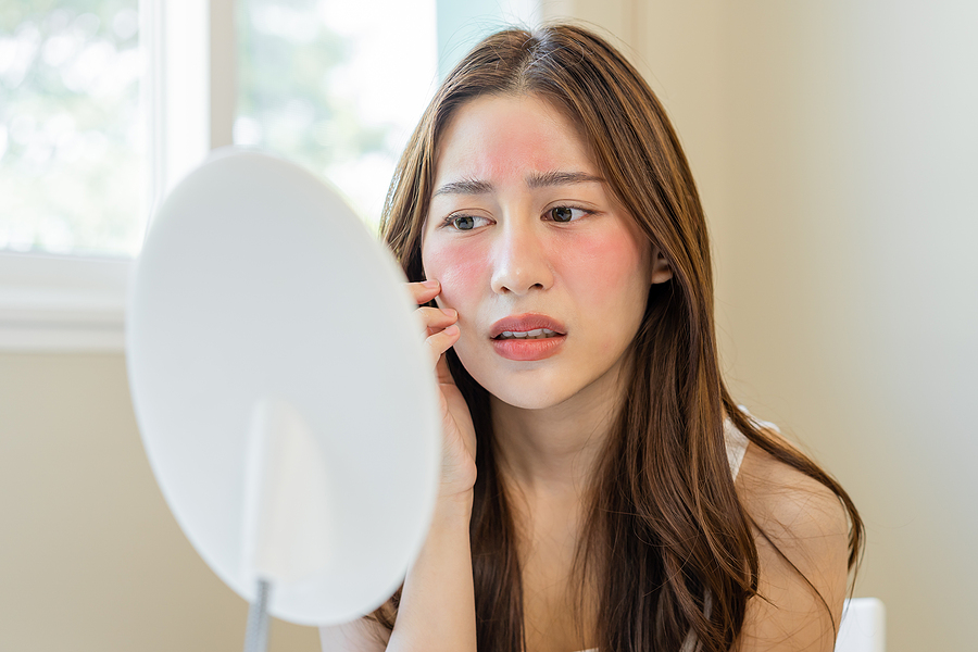 young brunette girl with red cheeks looking in mirror