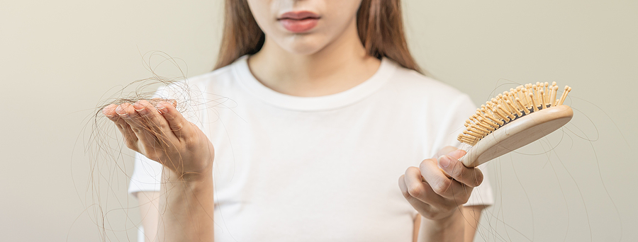 woman holding hair in one hand and brush in the other