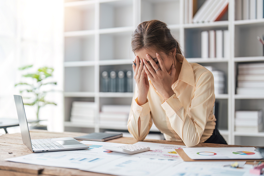 woman head in hands fatigued at desk