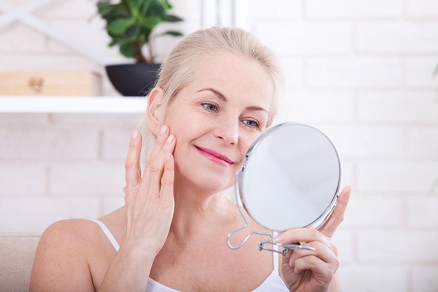 blonde mature woman looking at face in mirror