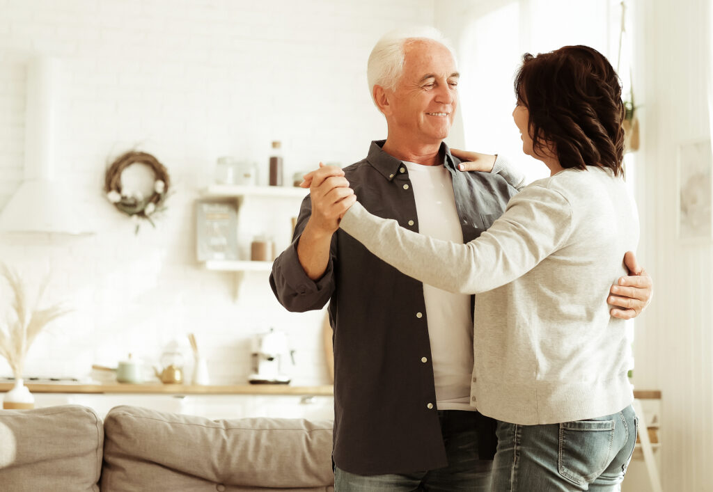 Carefree happy active old senior couple dancing in kitchen, with no inflammation.