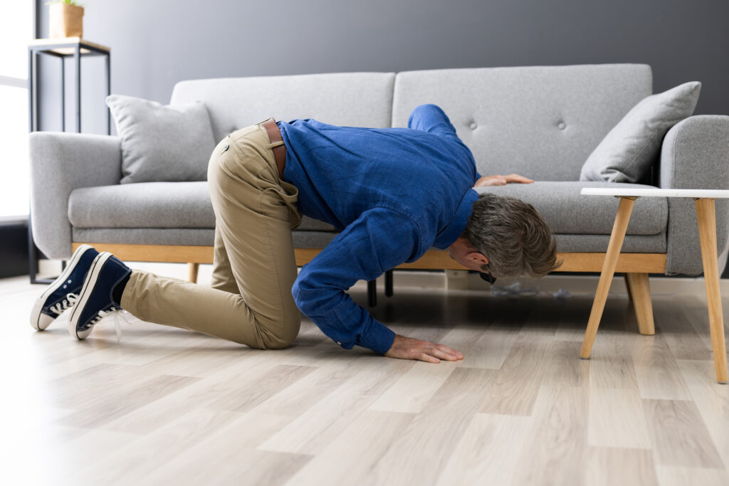 Man looking under the couch for lost phone or keys signifying memory loss and cognitive decline